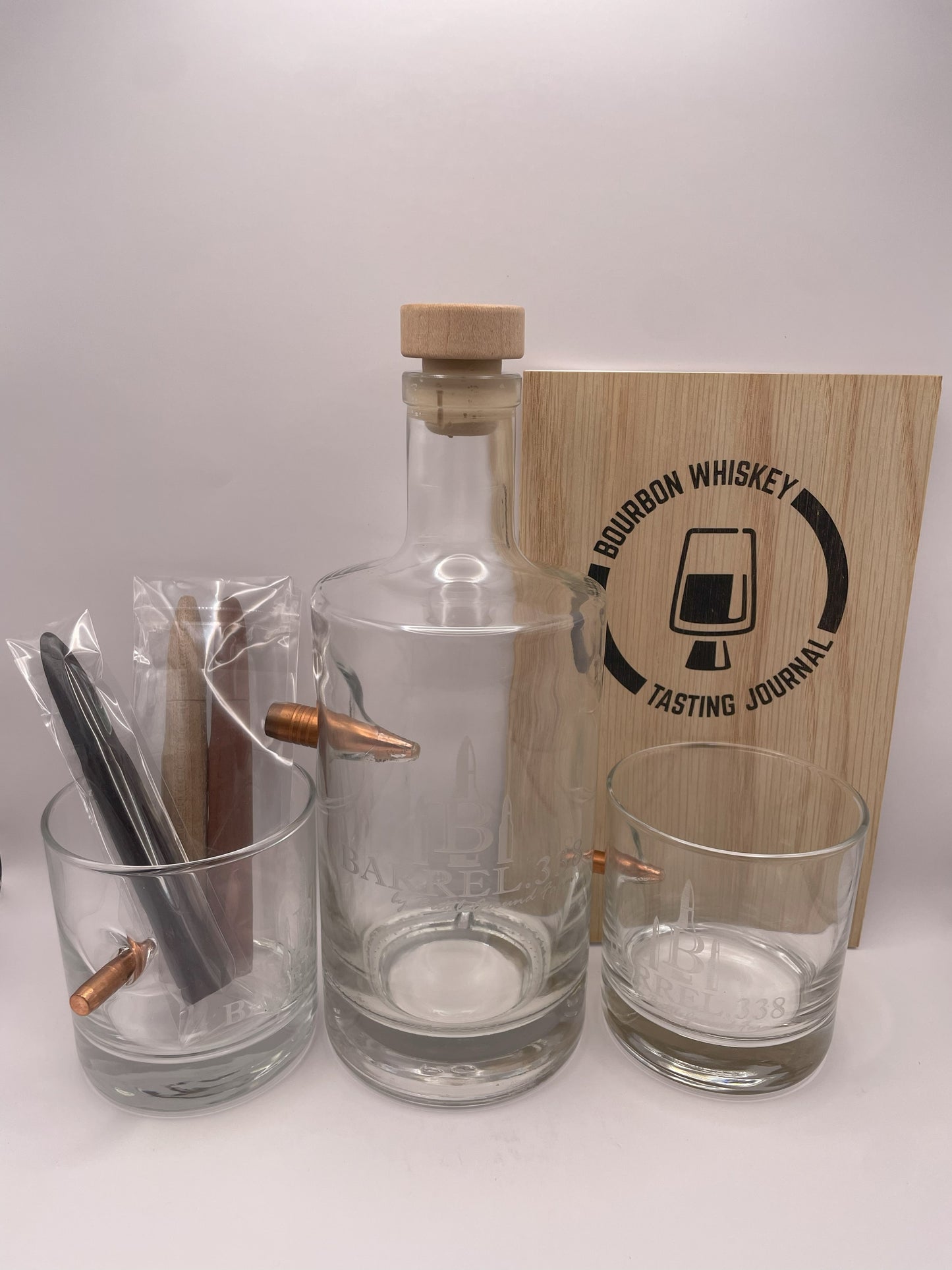 Image of a whiskey tasting journal gift box containing two rocks glasses, a decanter, and bourbon smoothing and aging infusion staves.